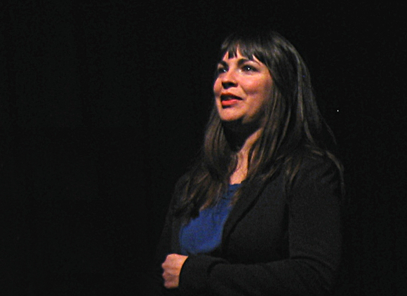 A woman stands on stand speaking.