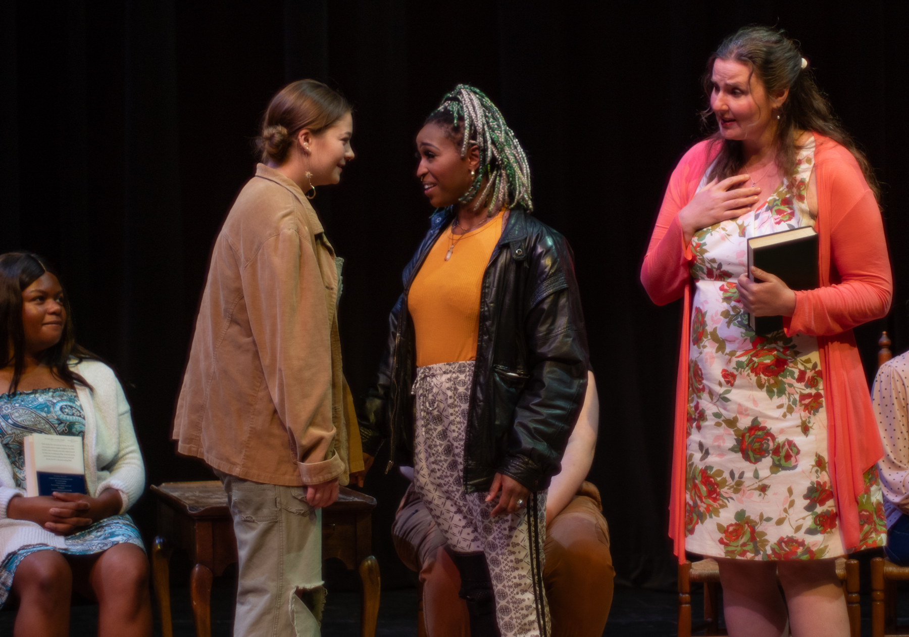 Two women smile at each other, another looks on with anticipation and another with confusion