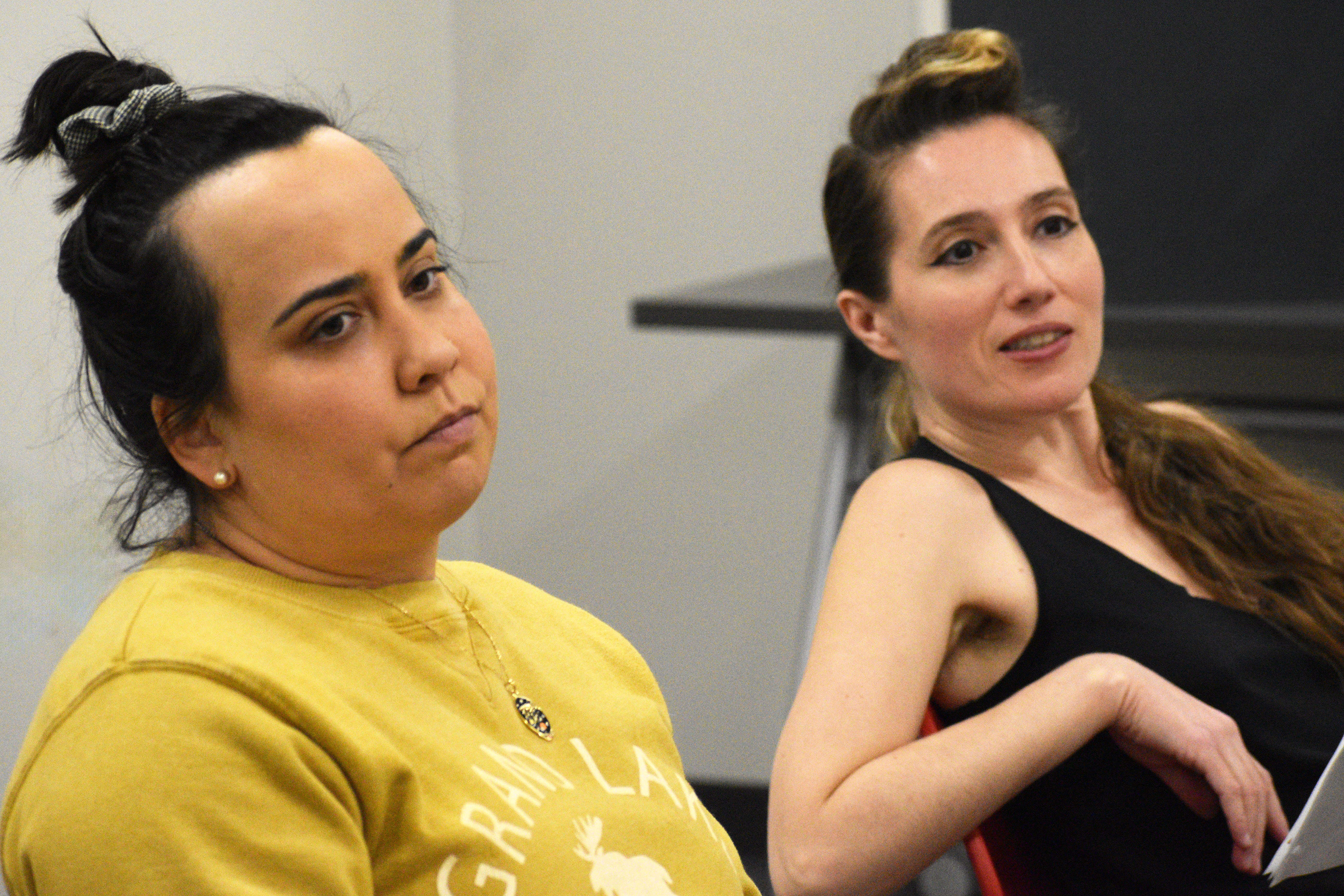 Two actors look out, one is disappointed in what they see, the other is amused.